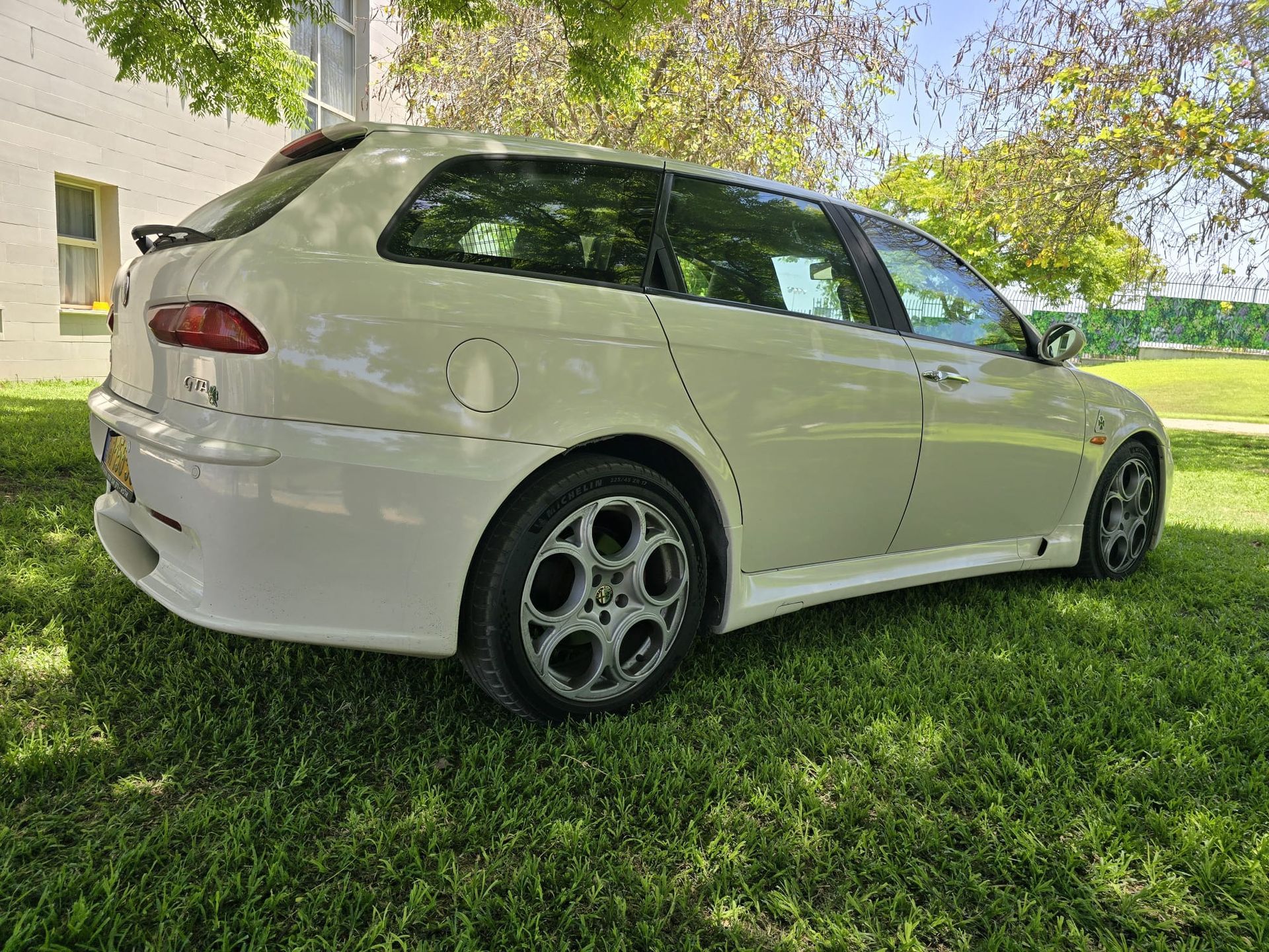 מכונית לבנה חונה בדשא מול בניין.