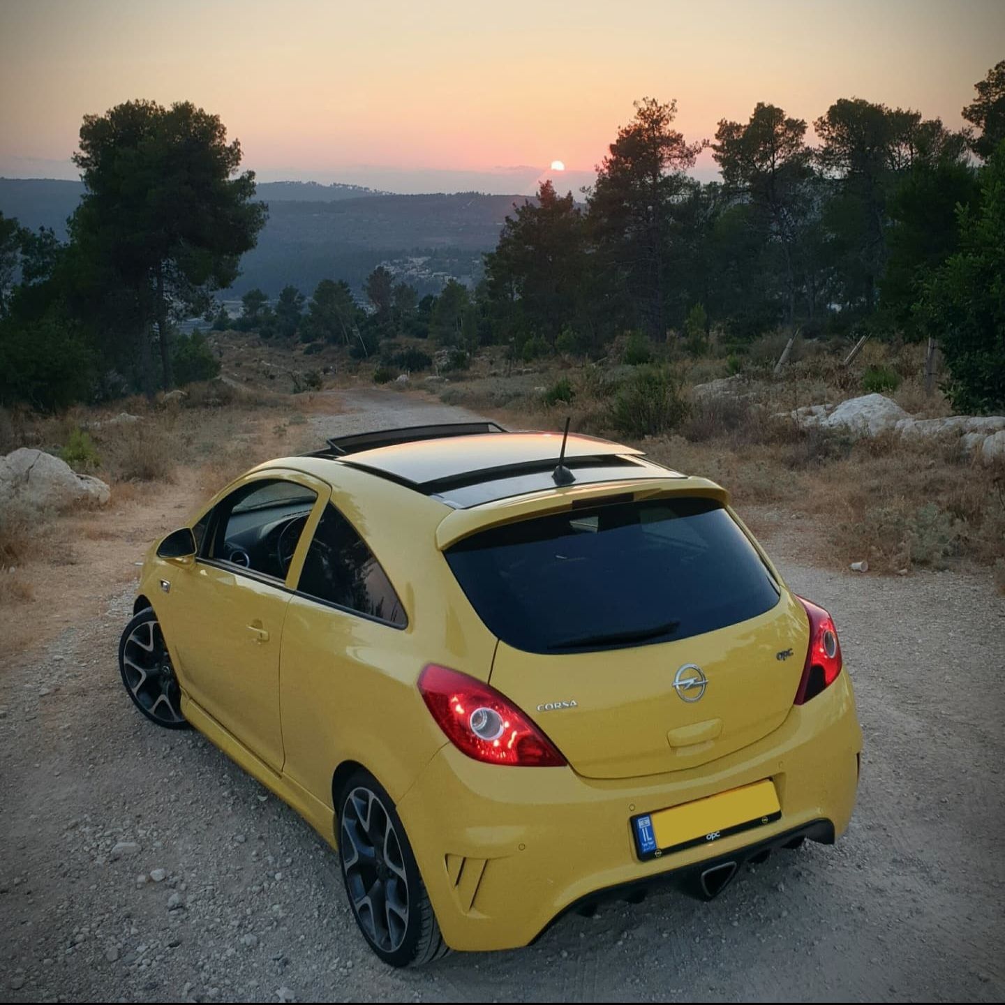 מכונית צהובה חונה על דרך עפר בשקיעה