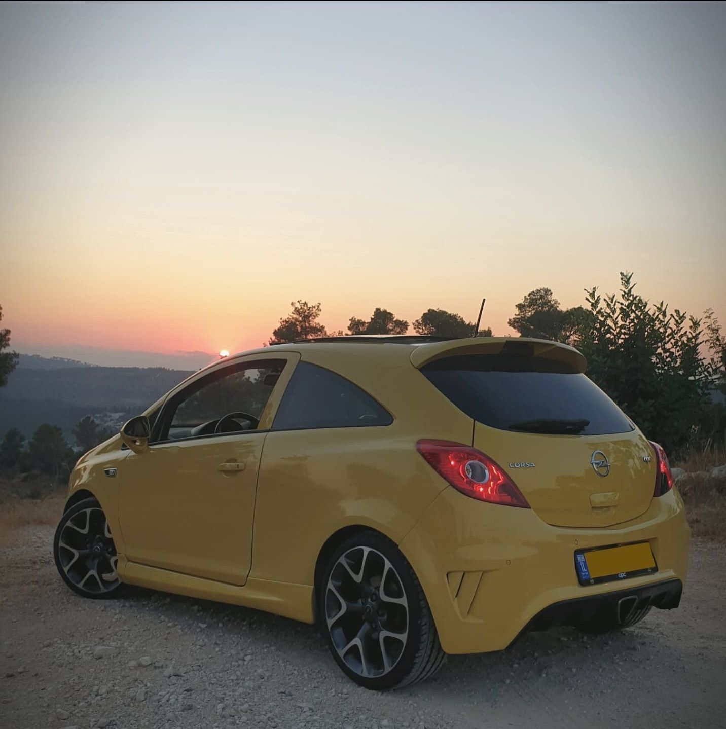 מכונית צהובה חונה על כביש כורכר בשעת השקיעה