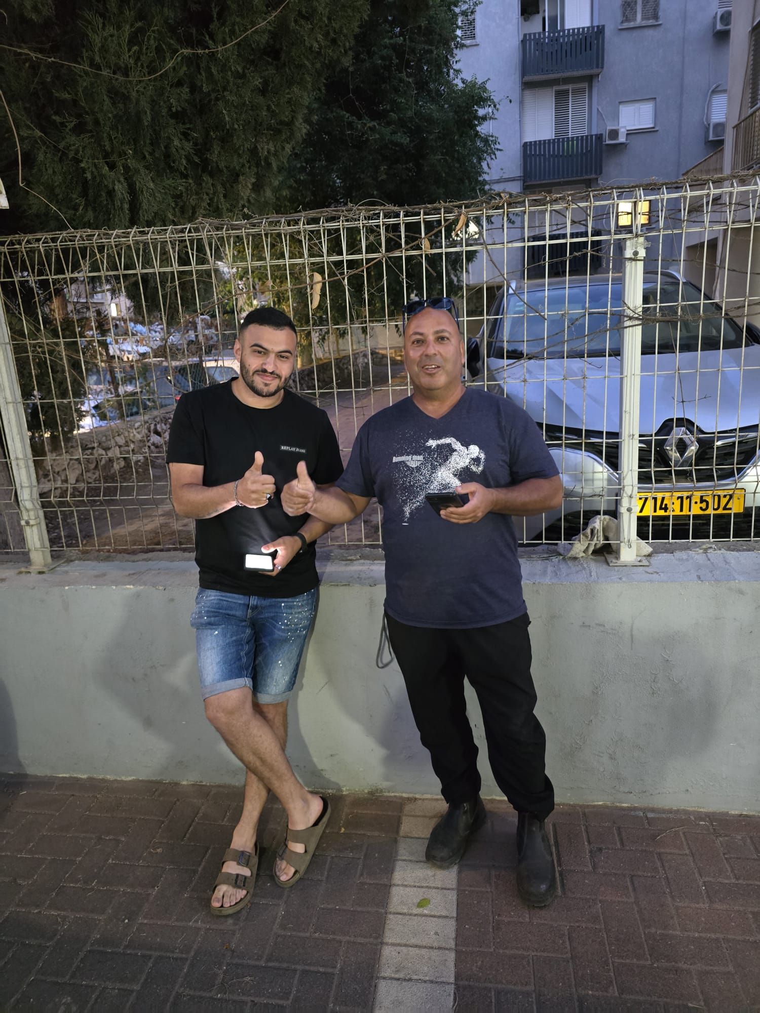 גבר עומד ליד מכונית אדומה.