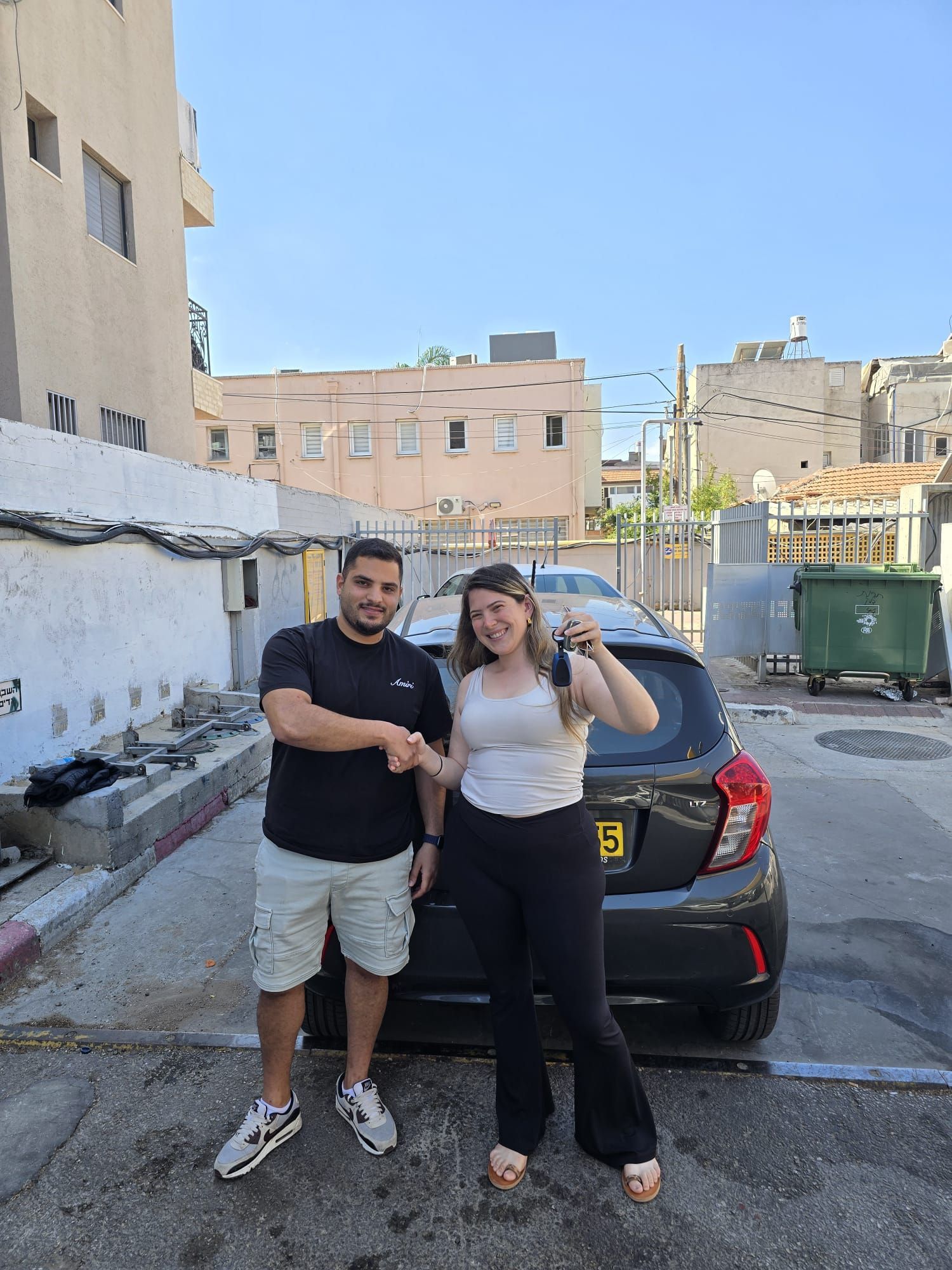 גבר ואישה לוחצים ידיים מול מכונית.