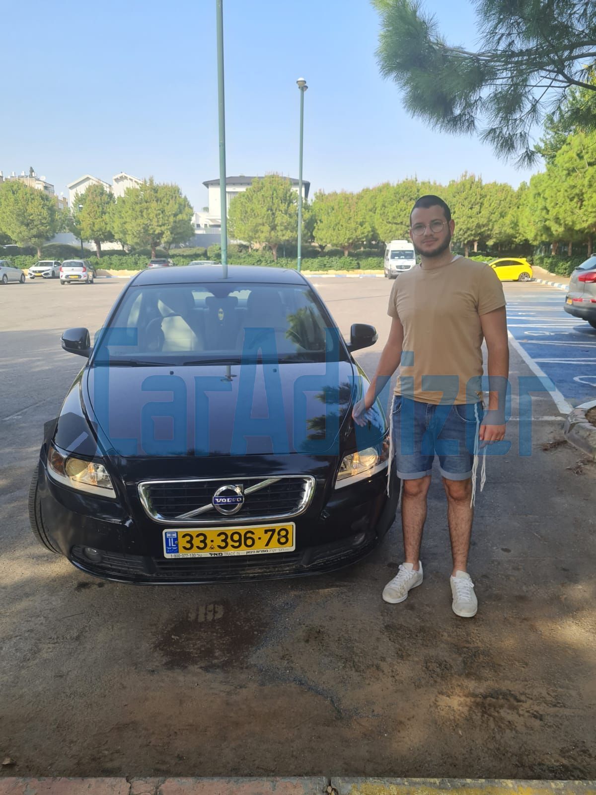 גבר עם קביים עומד מול מכונית וולבו במגרש חניה.