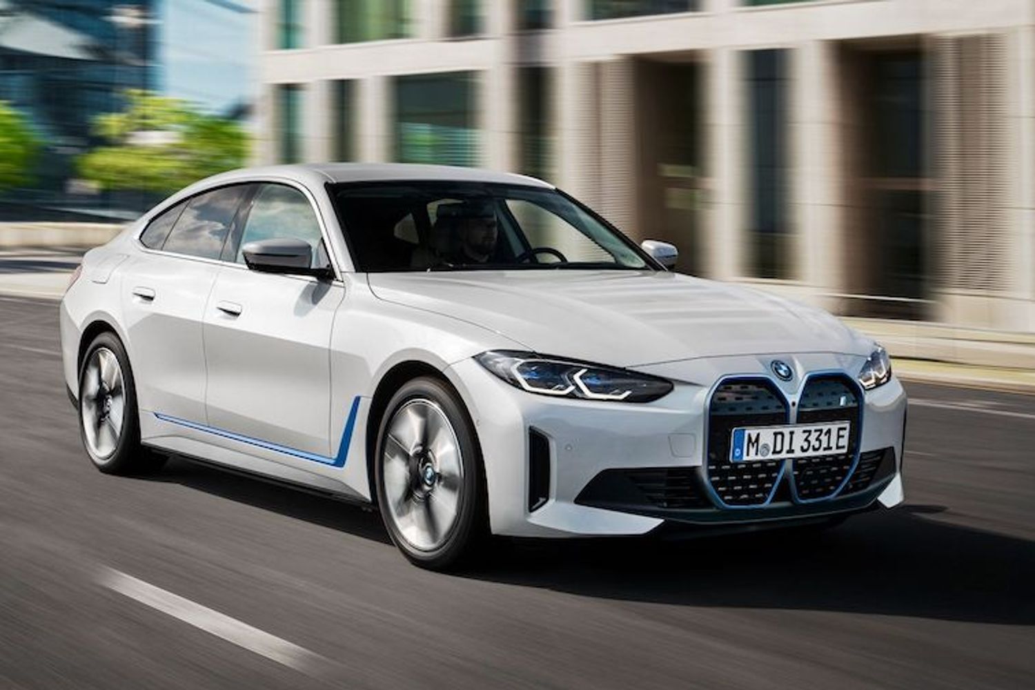 מכונית חשמלית לבנה bmw i4 נוסעת ברחוב בעיר.