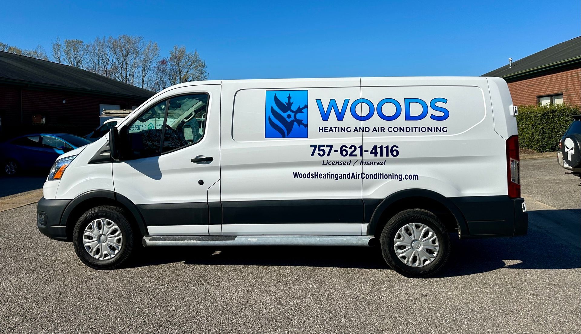 A white van with the word woods on it is parked in a parking lot.