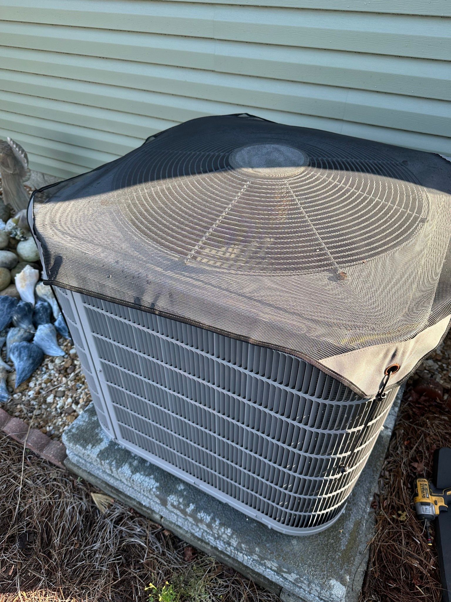 An air conditioner with a cover on it is sitting outside of a house.