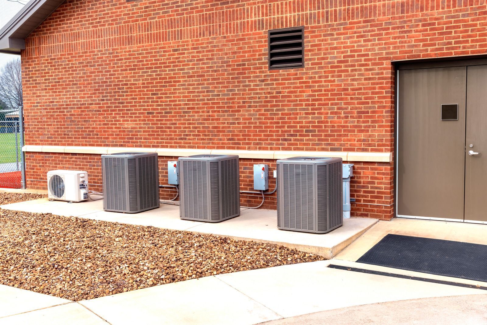 A row of air conditioners are sitting outside of a brick building.