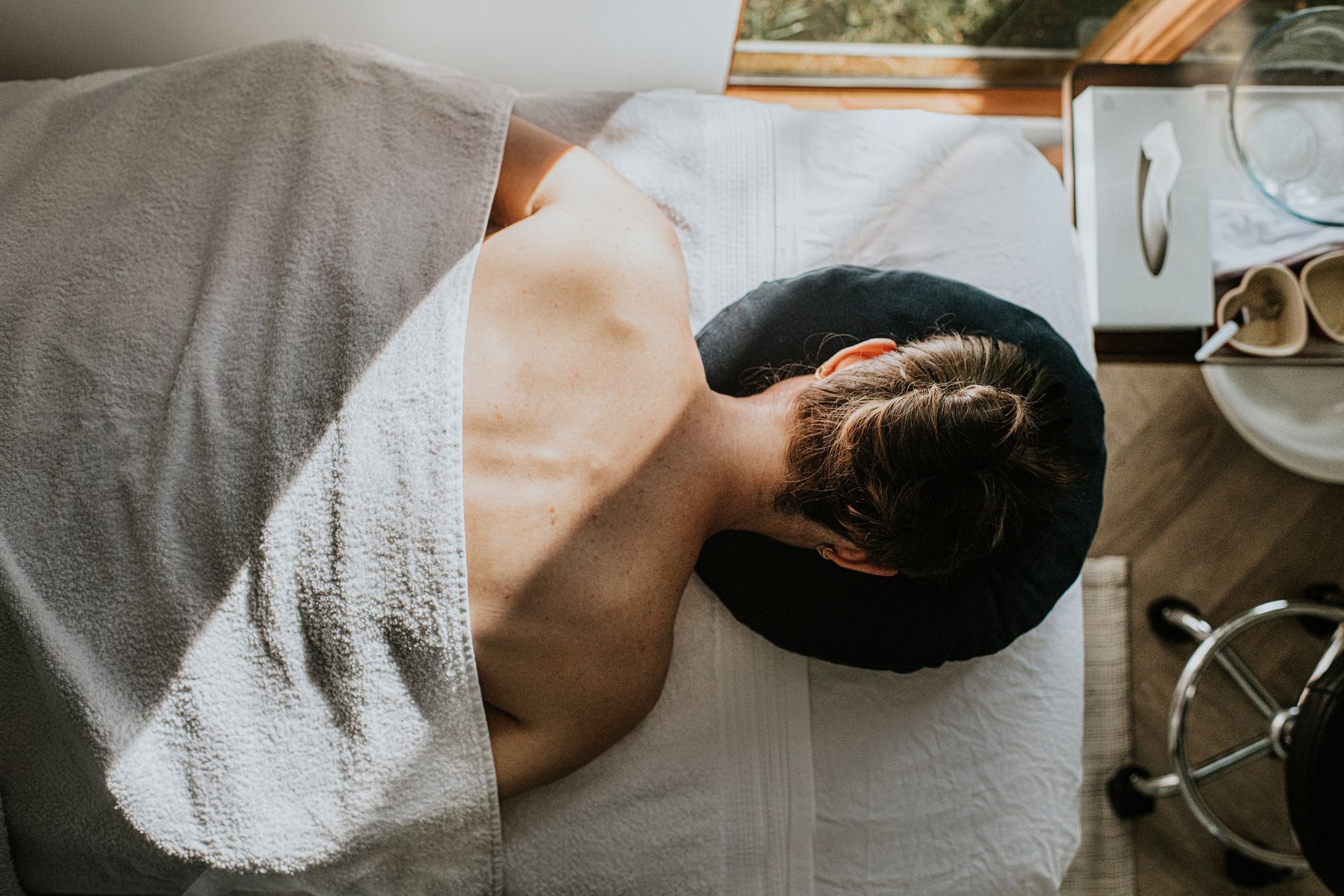 Man lying face down on massage table, partially covered with a towel.