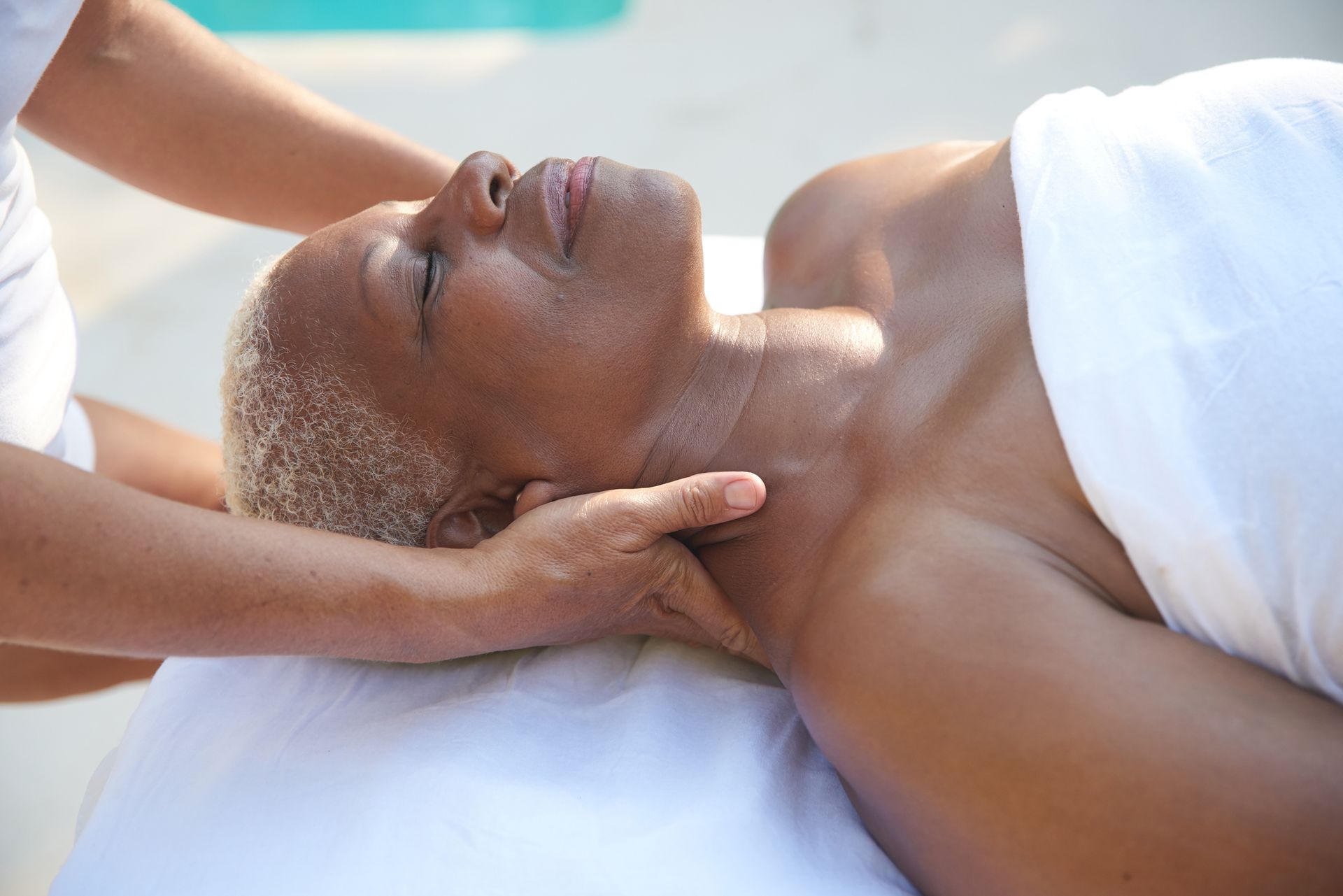 Woman receiving a neck massage at an outdoor spa.