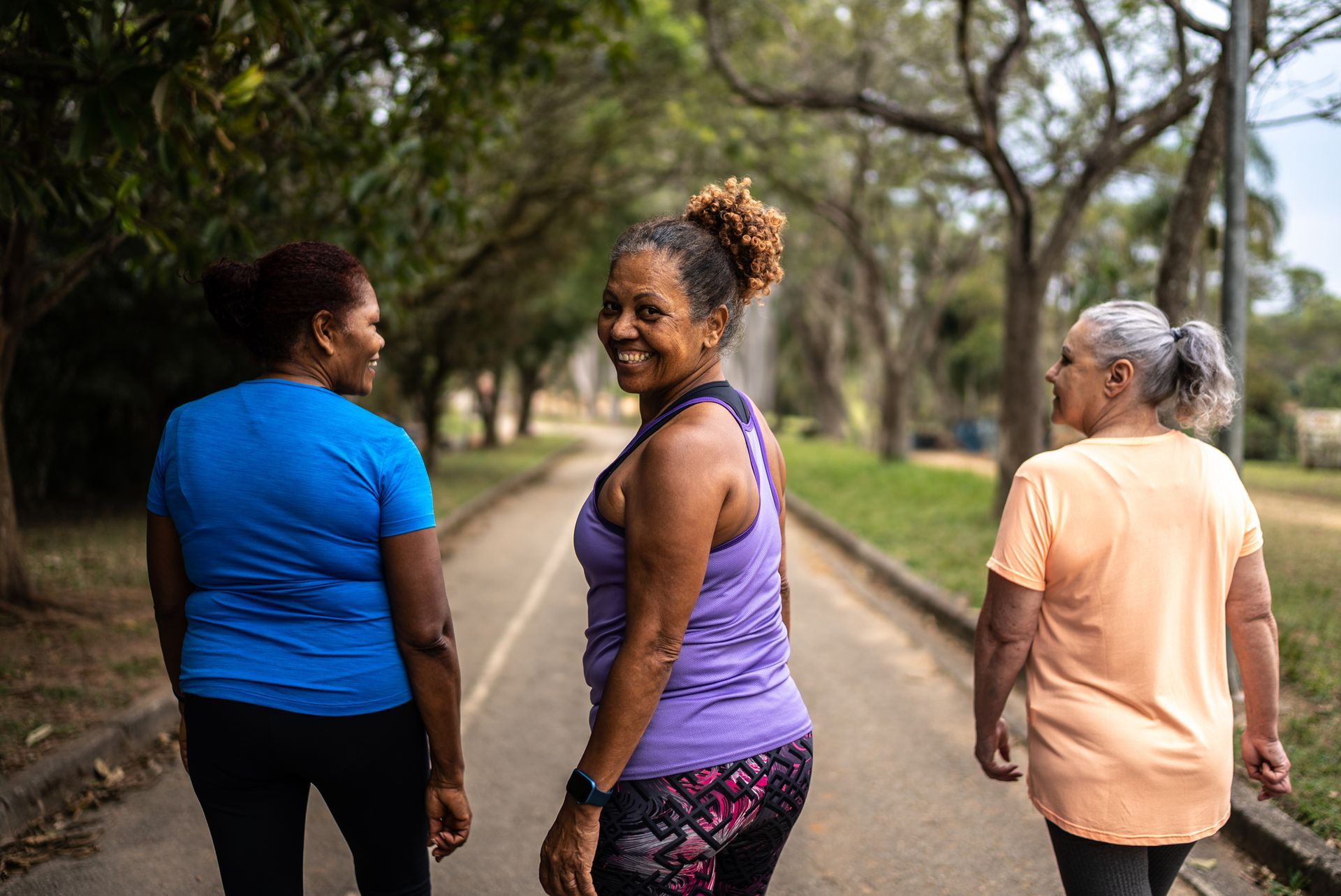 Three women walking on a path in a park.