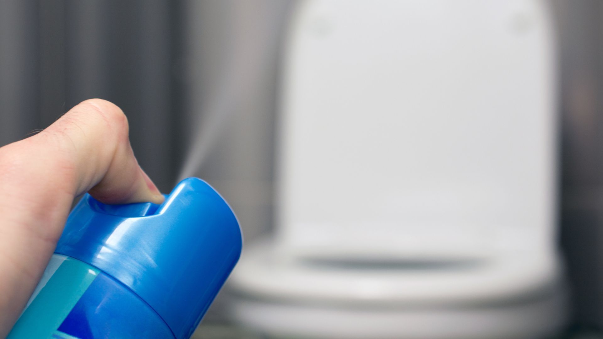 A person is spraying a toilet with a spray bottle.