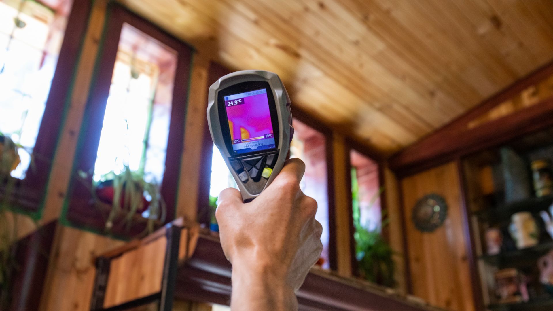 A person is holding a thermal camera in their hand in a room.