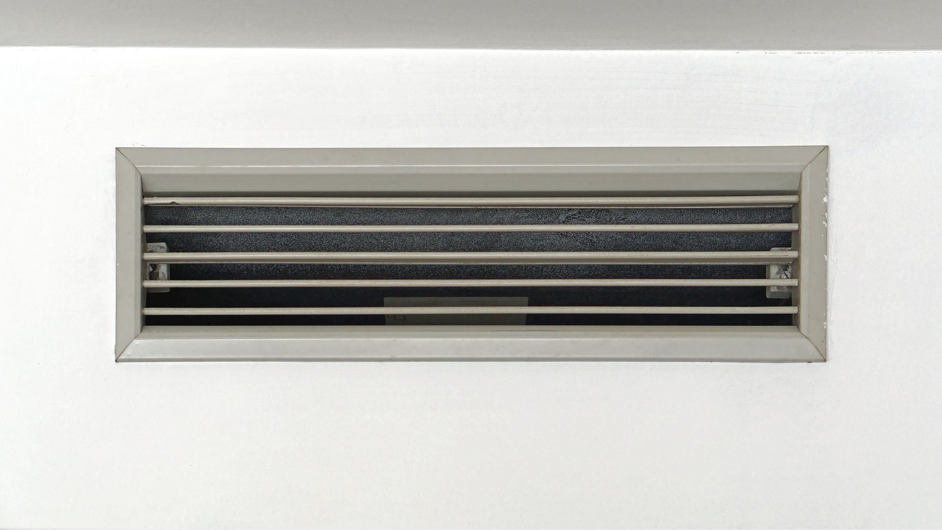 A white air vent on a white wall.