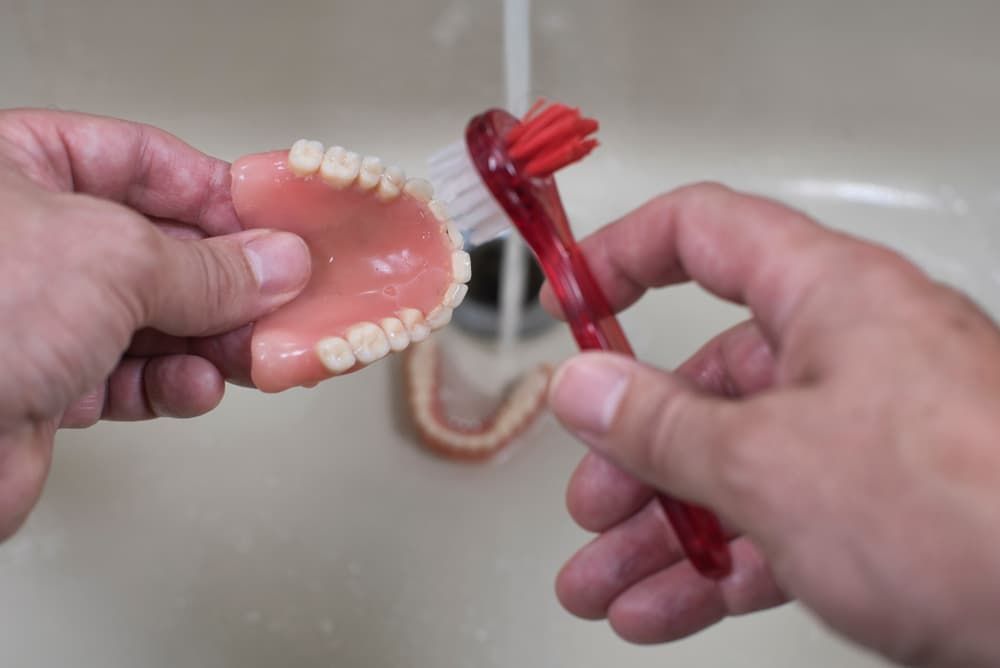 Brushing Dentures In A Sink Under Running Water - Dentures in Moss Vale, NSW