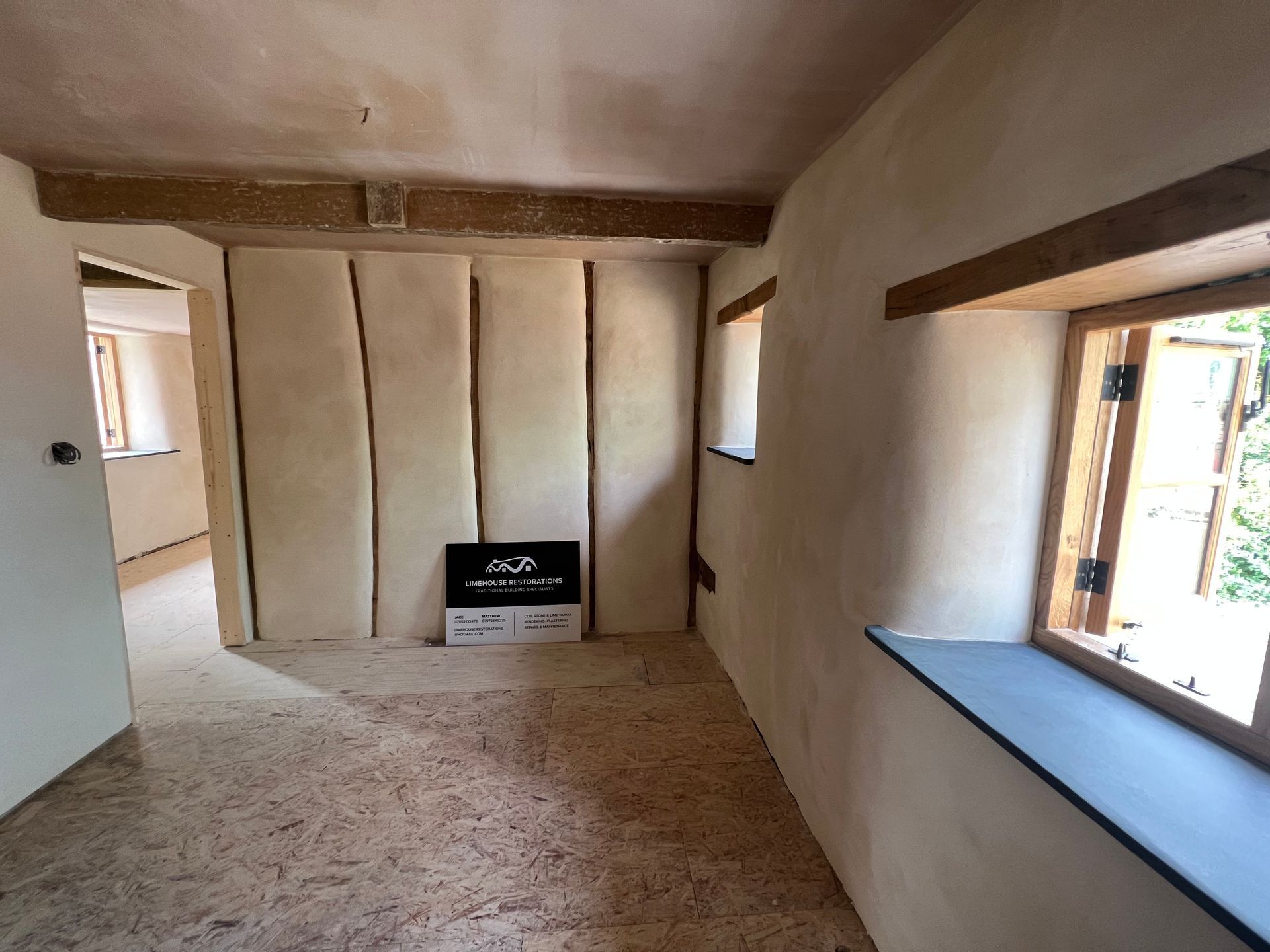 An empty room with a window and a sign on the wall.