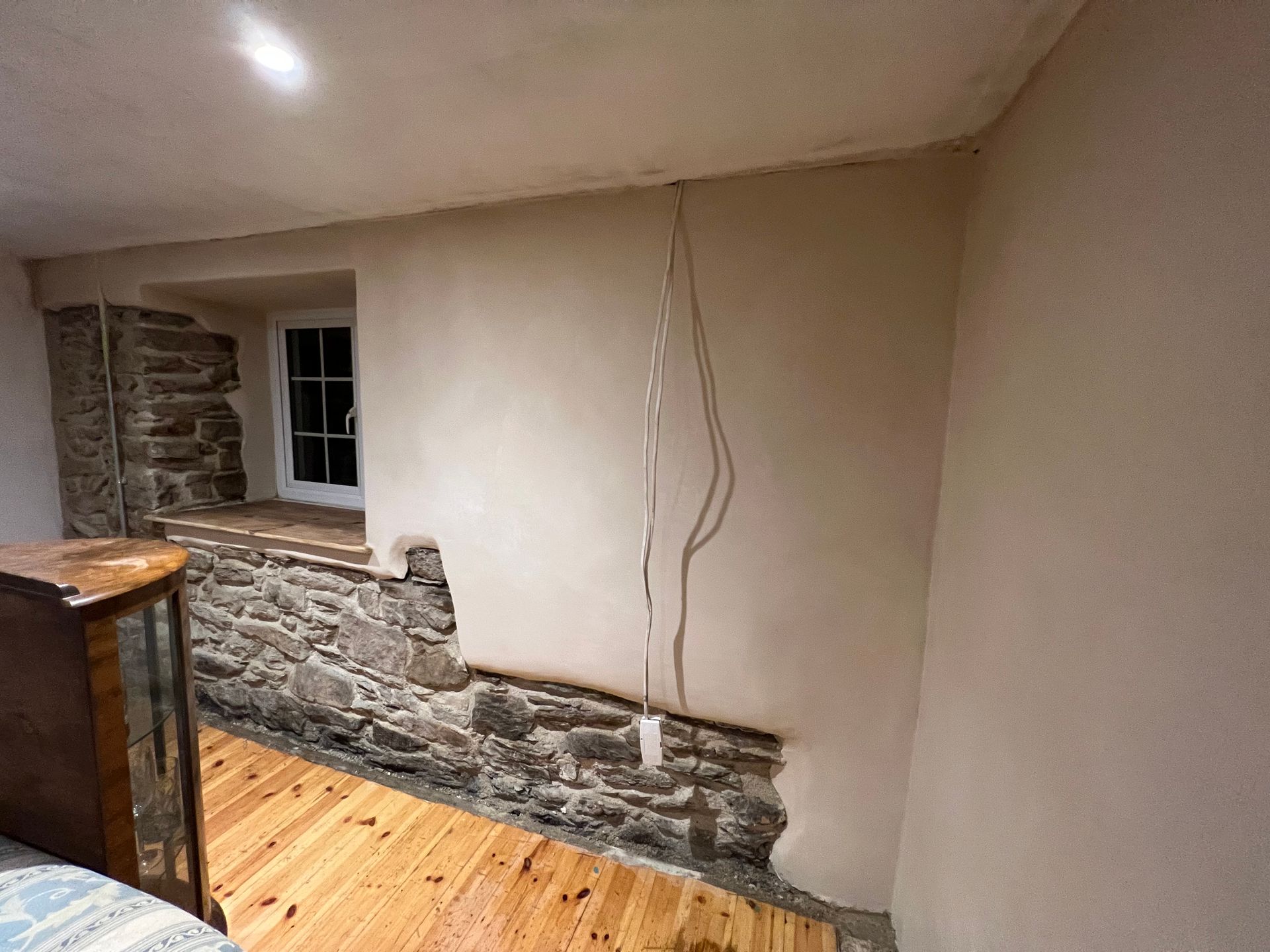 A room with a wooden floor and a stone wall.