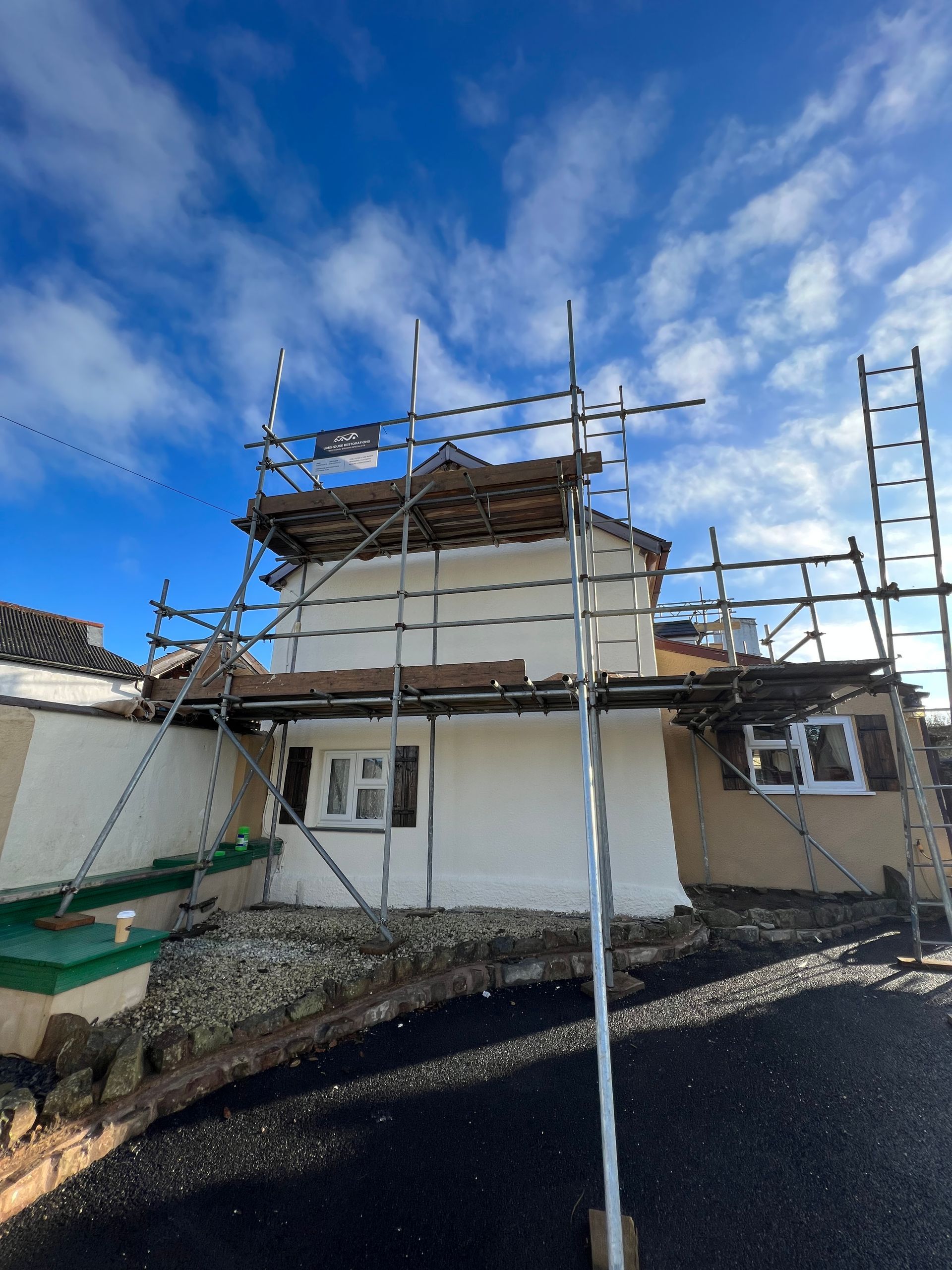 A house with scaffolding around it and a blue sky in the background.