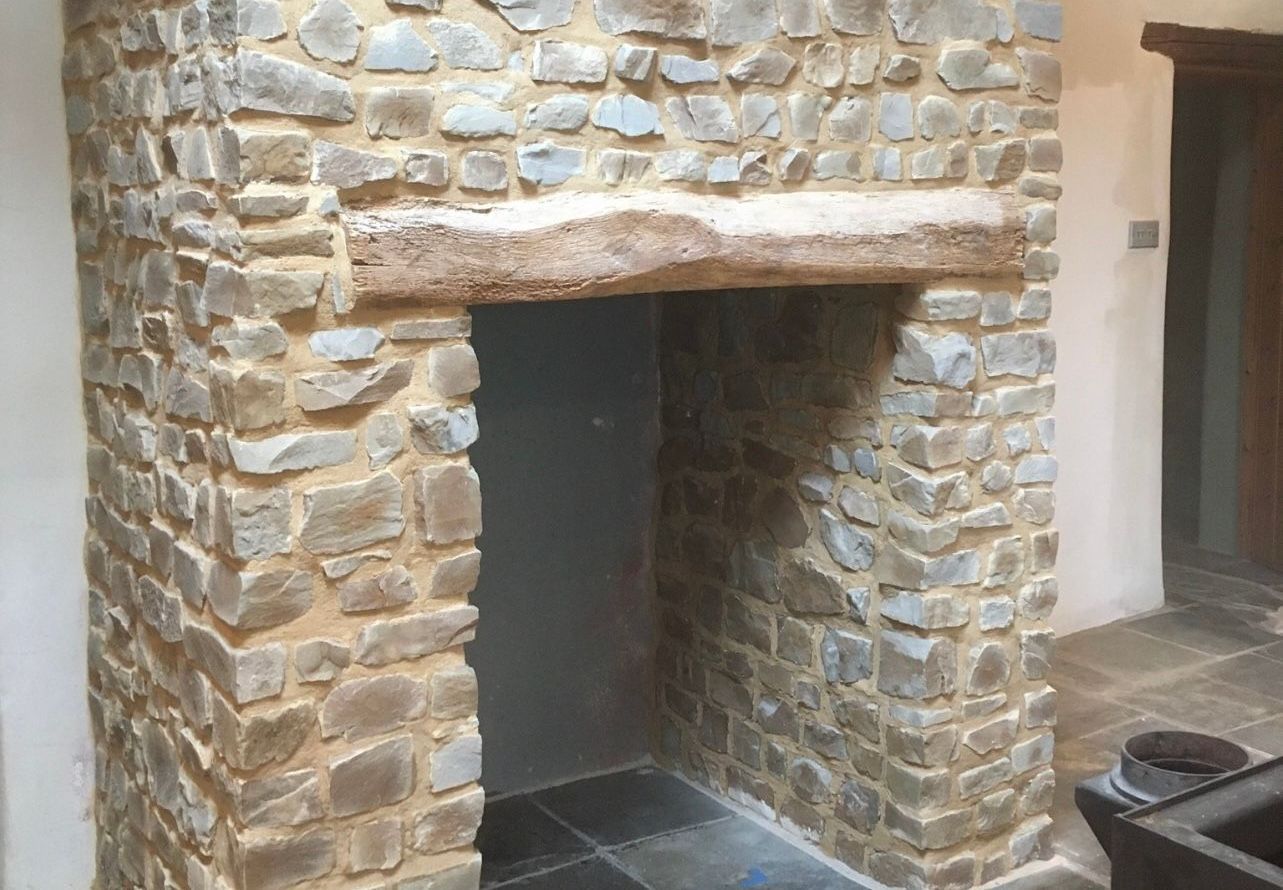 A stone fireplace with a wooden mantel in a room.