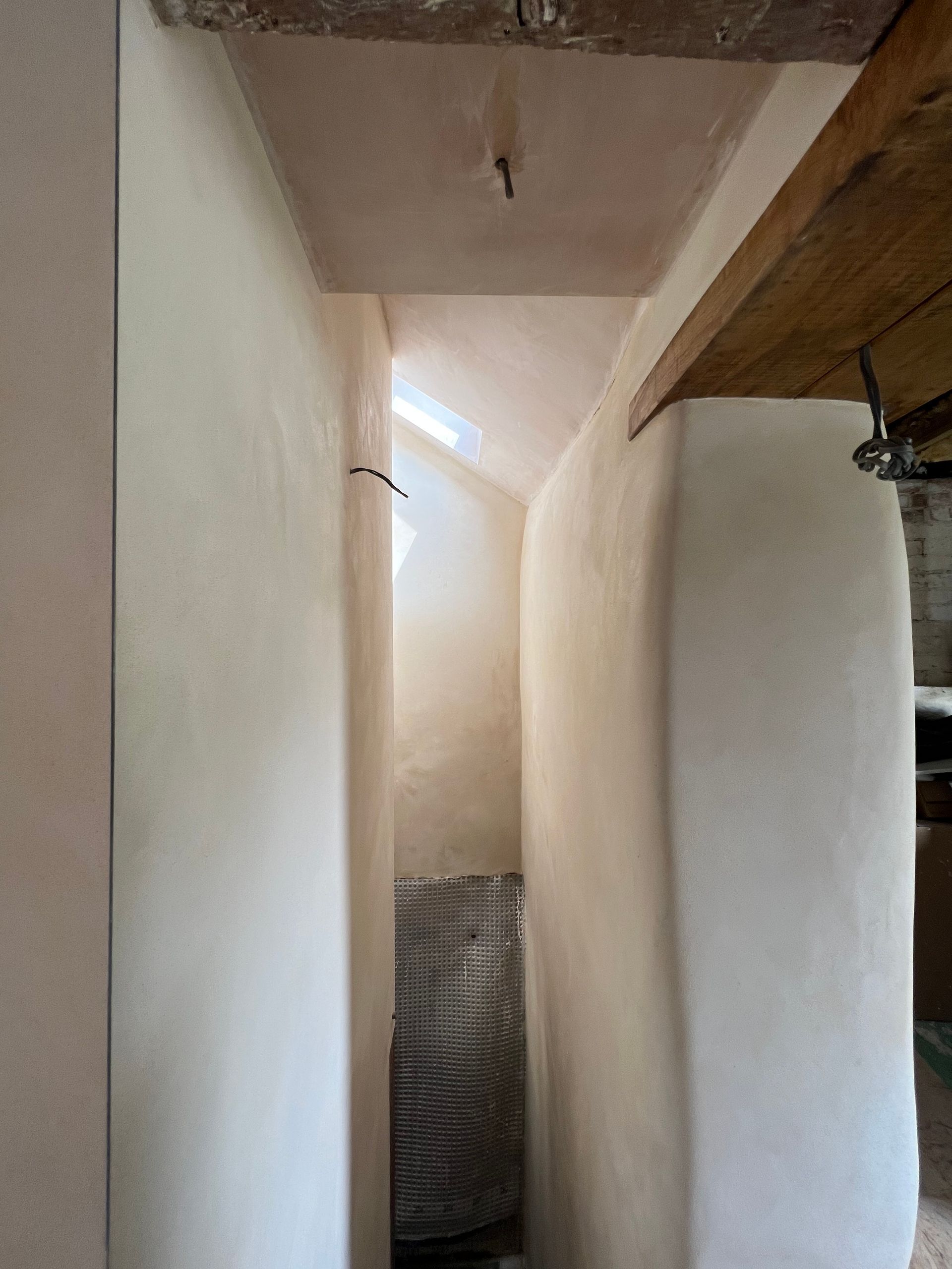 A narrow hallway with white walls and a wooden ceiling.
