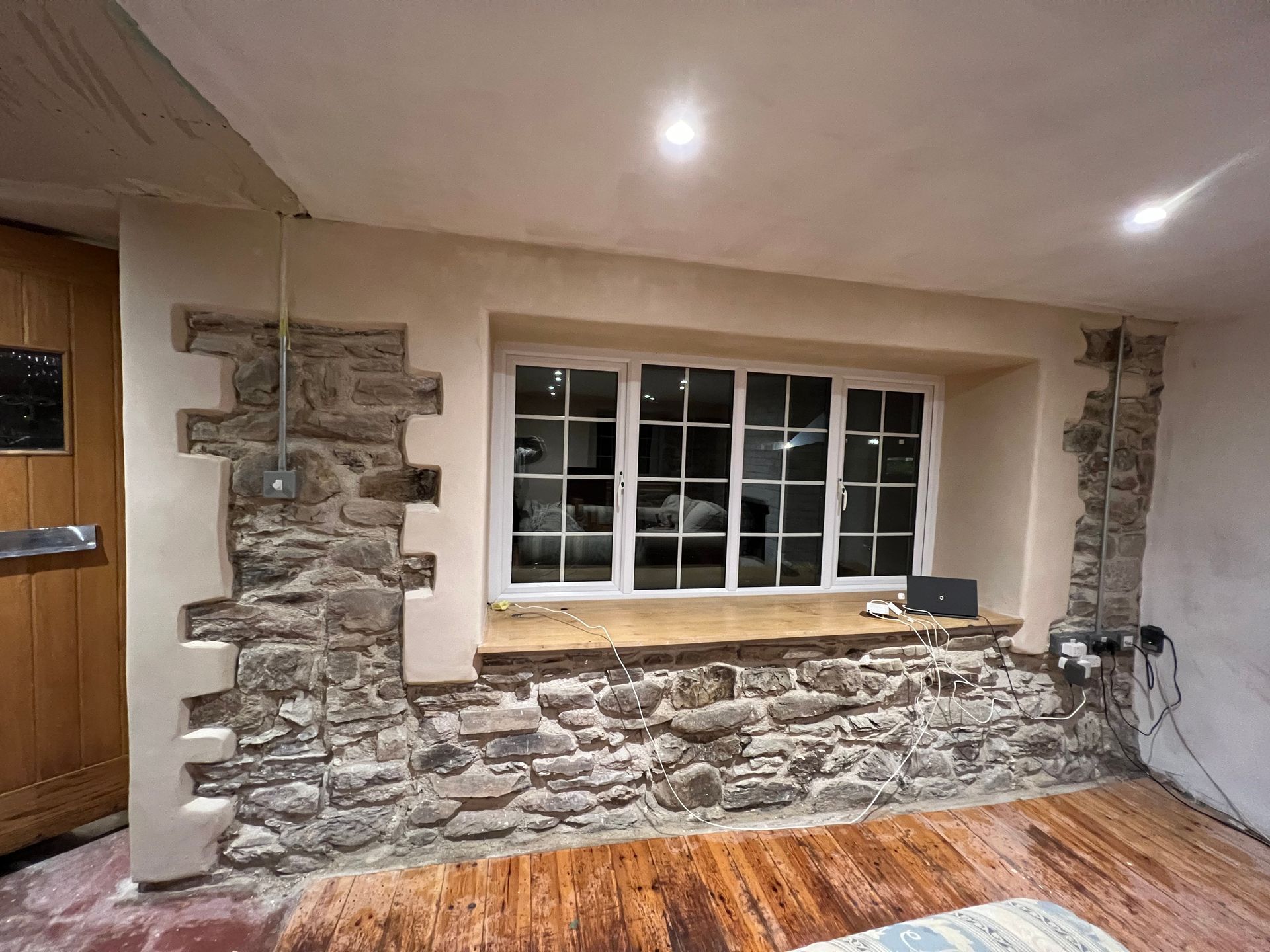 A living room with a stone wall and a large window.