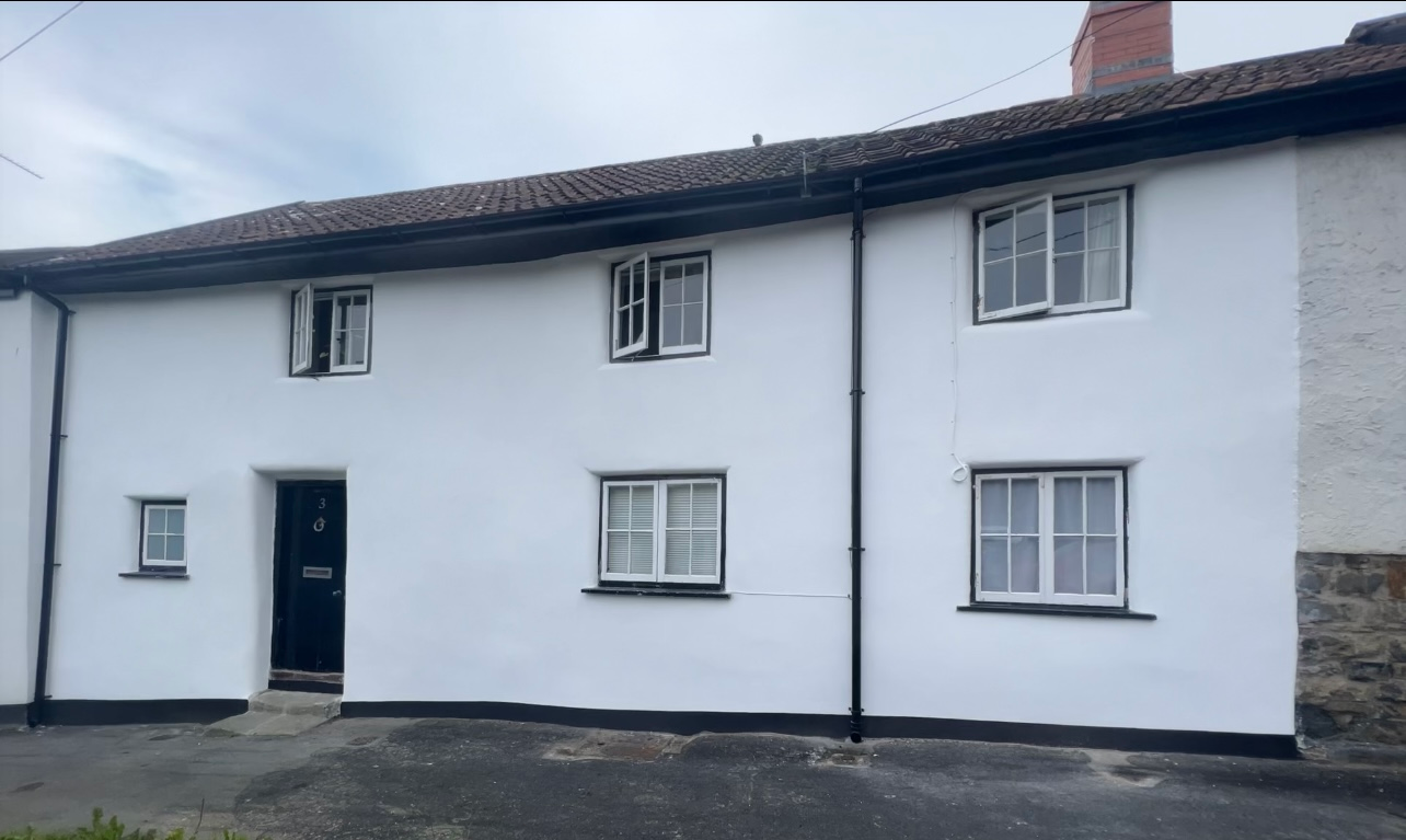 A white house with black trim and windows on a cloudy day.