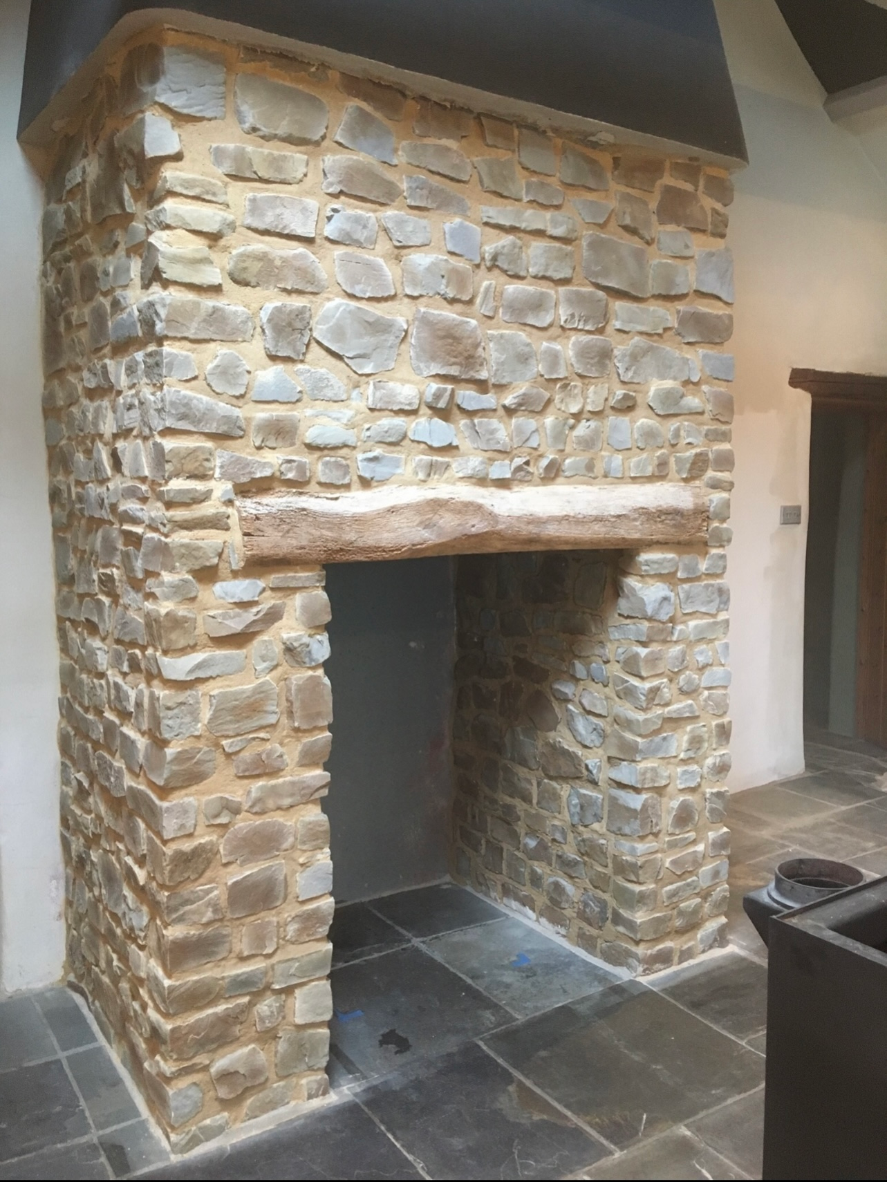 A stone fireplace with a wooden mantle in a living room