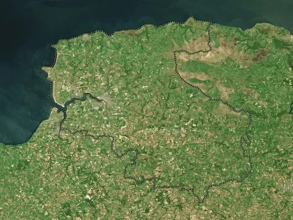 An aerial view of a green landscape with a body of water in the background.