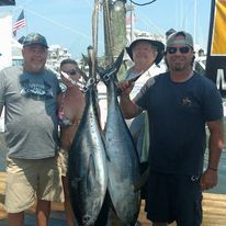 A group of men are standing next to each other holding fish on a dock.
