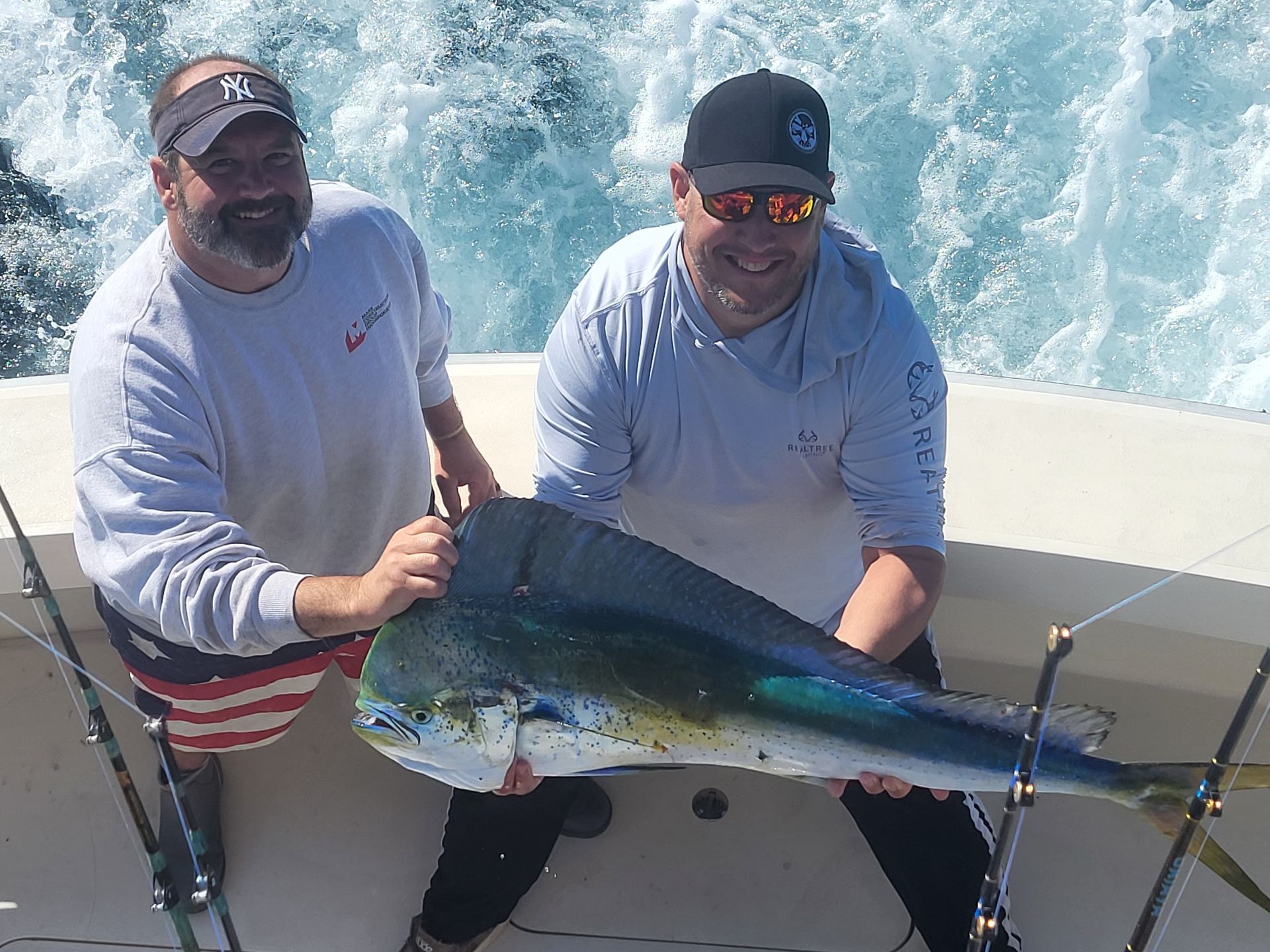 Two men on a boat holding a large fish