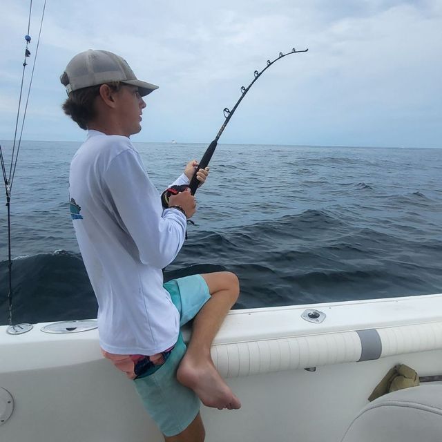 A man is fishing on a boat in the ocean