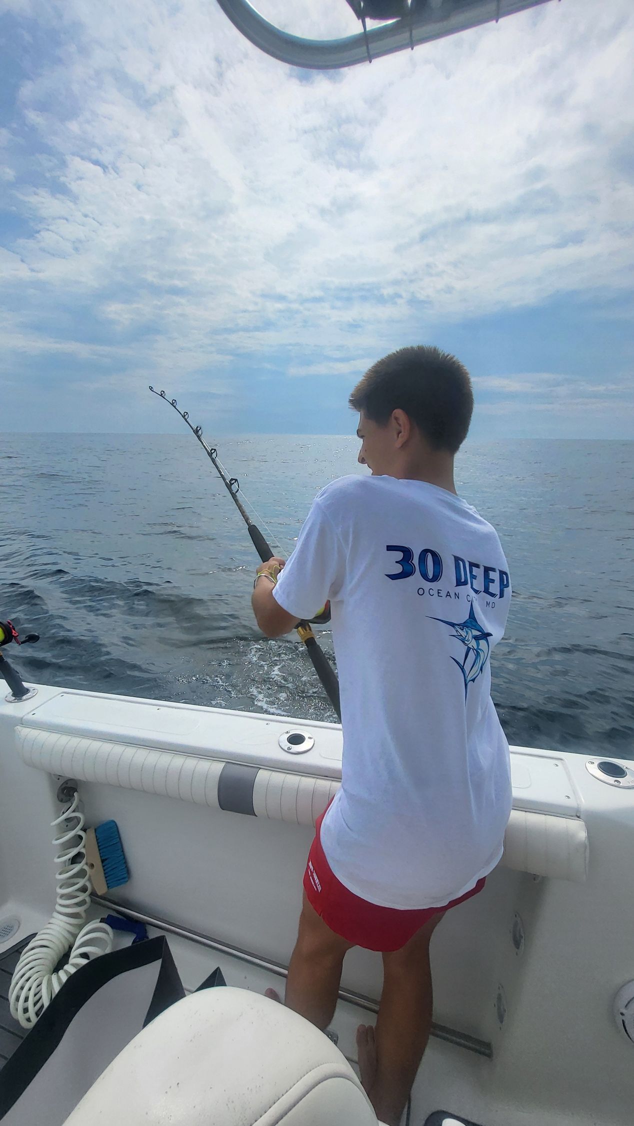 A boy on a boat with a shirt that says 30 Deep on it