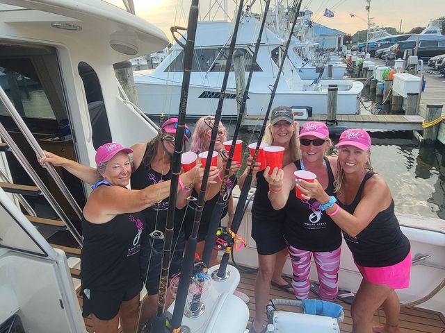 A group of women standing on a boat holding red cups