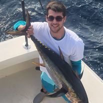 A man is holding a large fish on a boat.