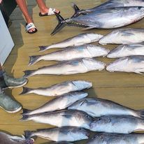 A bunch of fish are sitting on top of each other on a wooden floor.