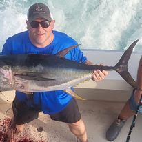 A man is holding a large fish on a boat.