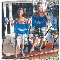 Two young boys are standing on a boat holding flags.