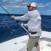 A man is fishing on a boat in the ocean.
