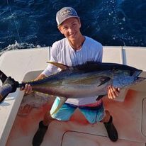 A young man is holding a Yellow FIn Tuna on 30 Deep Sportfishing Boat.