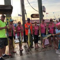 A group of people are standing next to each other holding fish.