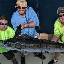 Three men are holding a large fish on a boat.