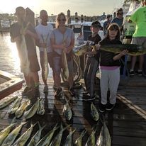 A group of people are standing on a dock holding fish.
