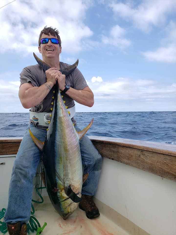 A man is sitting on a boat holding a large fish