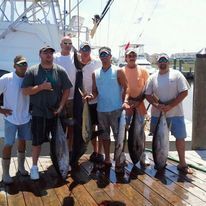 A group of men are standing on a dock holding fish.