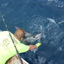 A man is fishing with a marlin in the ocean.