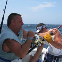 Two men are fishing on a boat in the ocean.