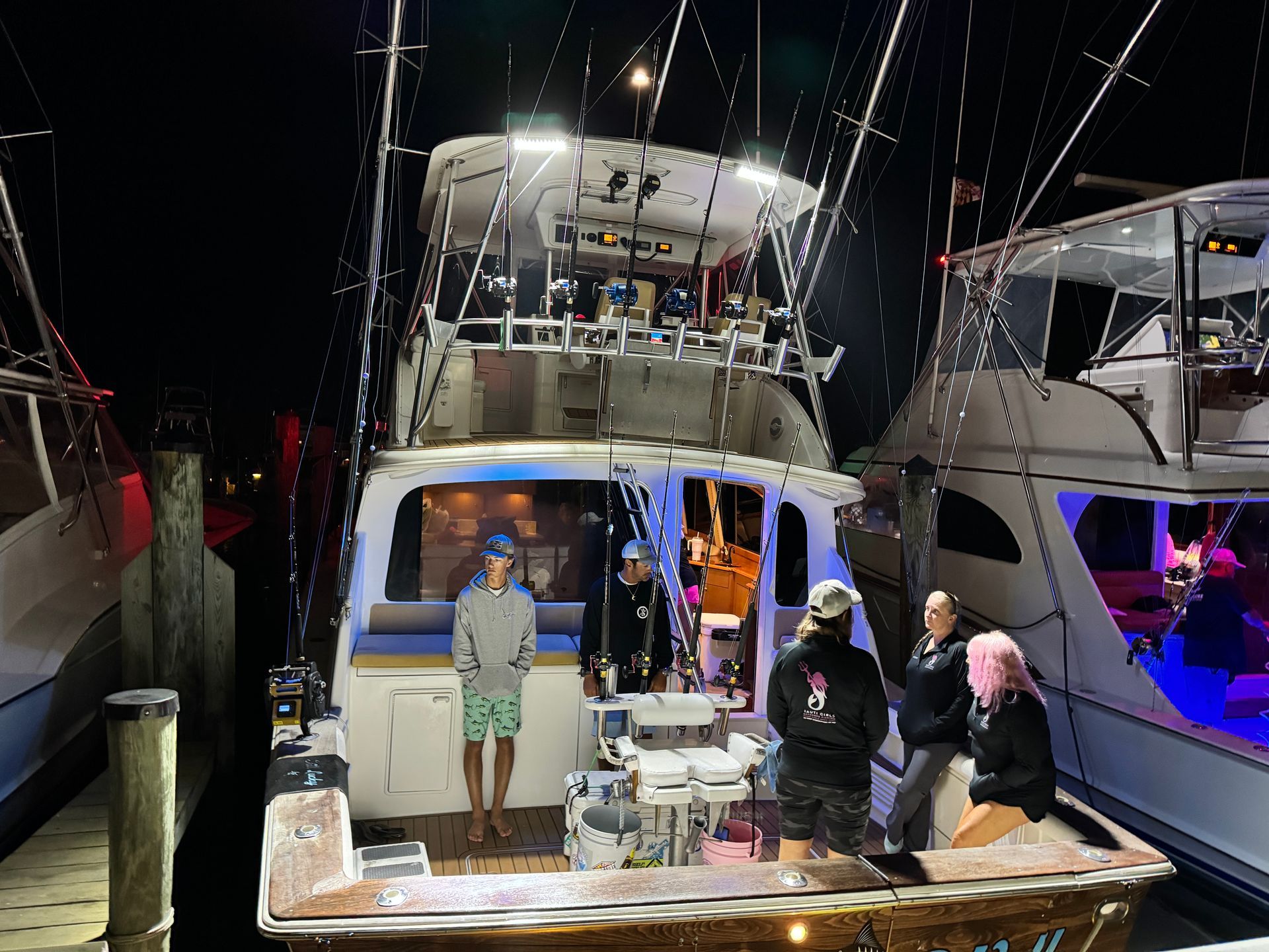 A group of people standing on the back of a boat at night