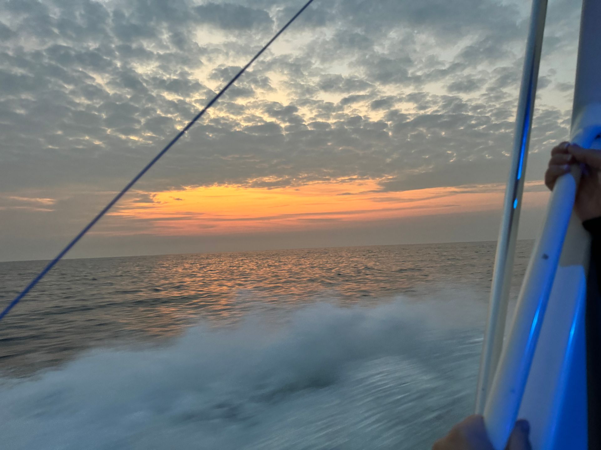 A person on a boat looking out over the ocean at sunset
