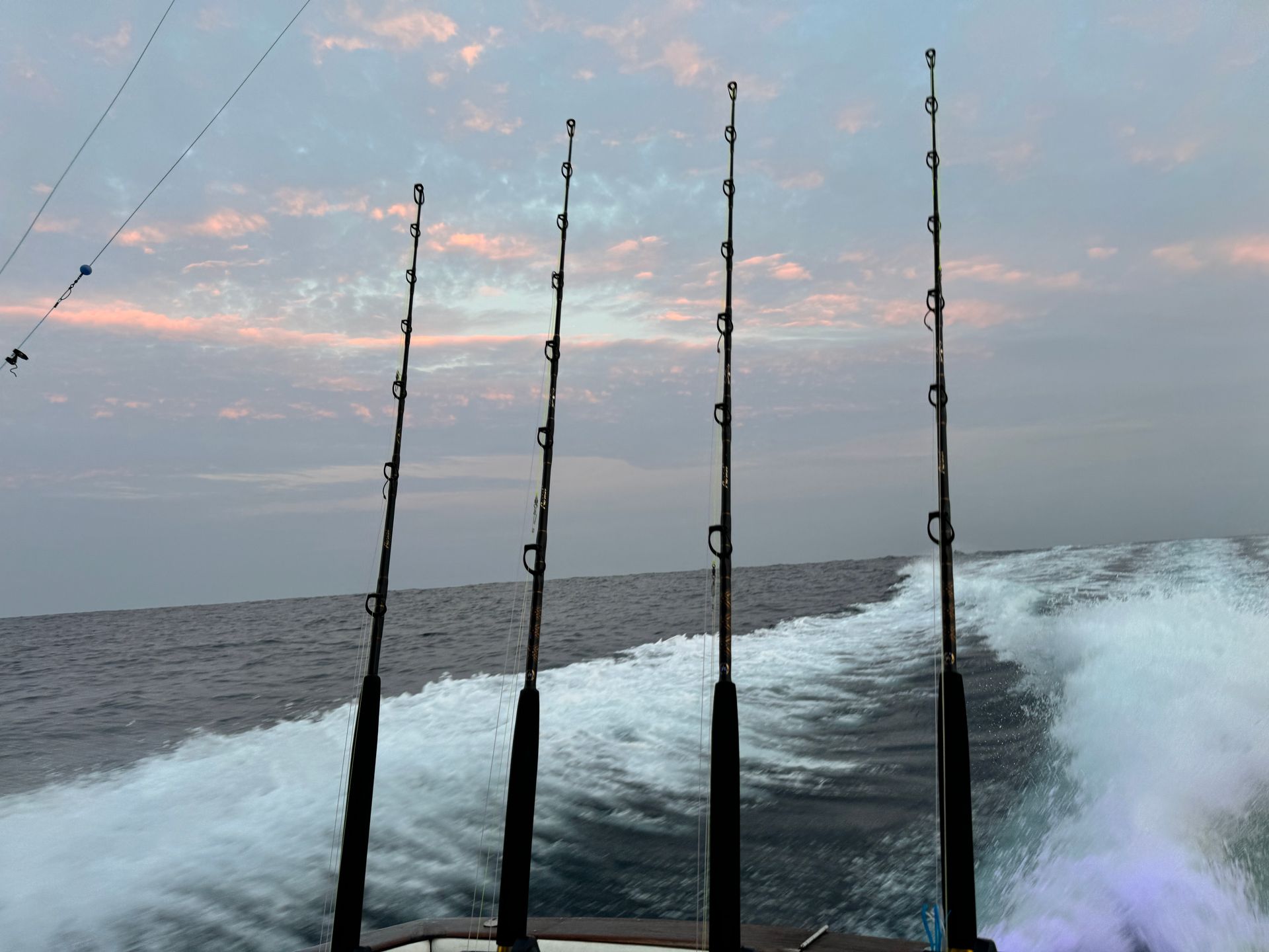 Several fishing rods are on a boat in the ocean