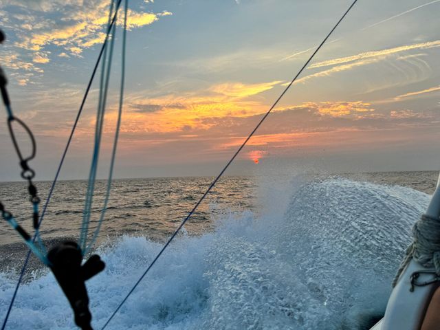 A boat is going through the ocean at sunset