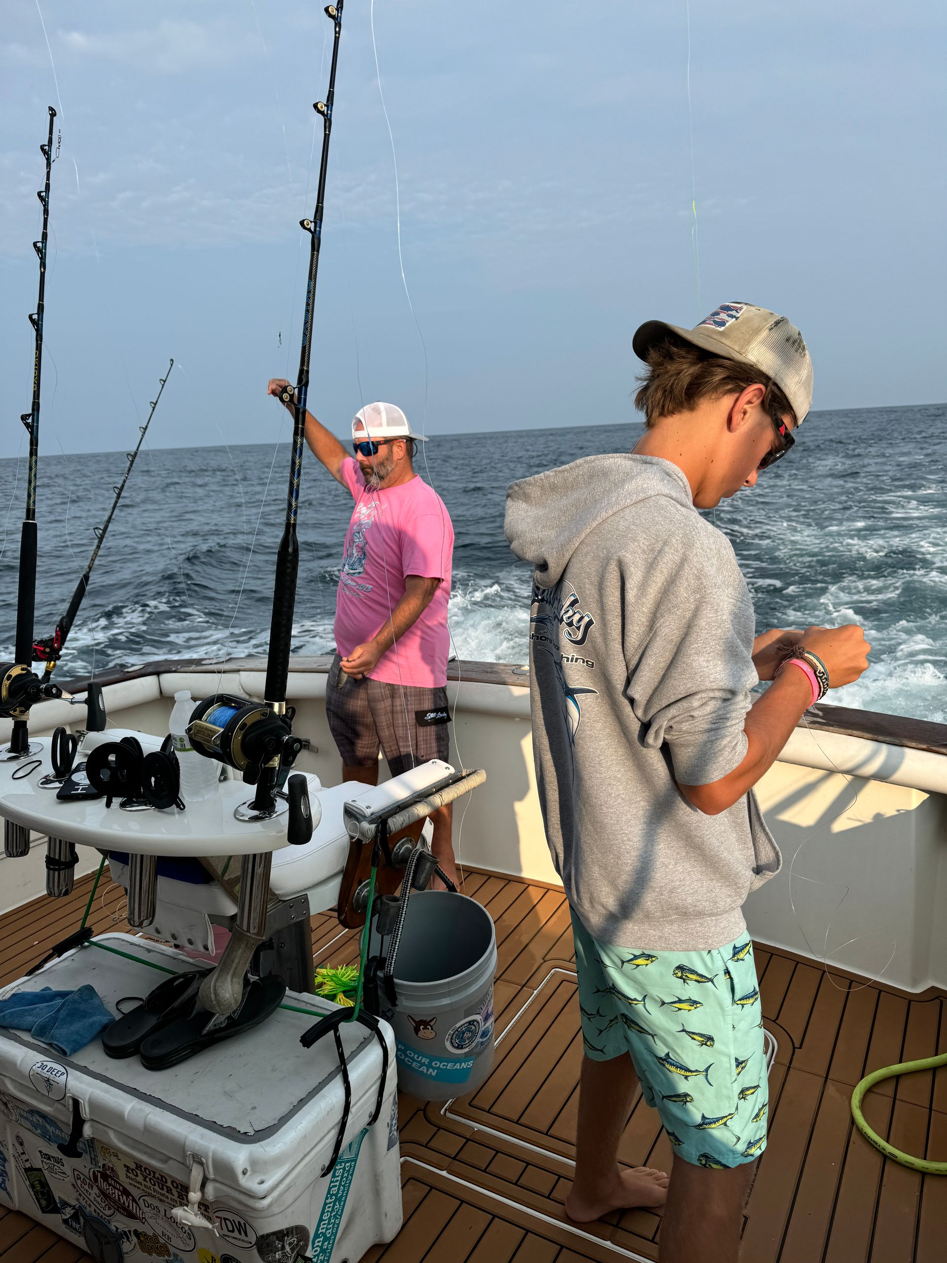 A man in a pink shirt is fishing on a boat