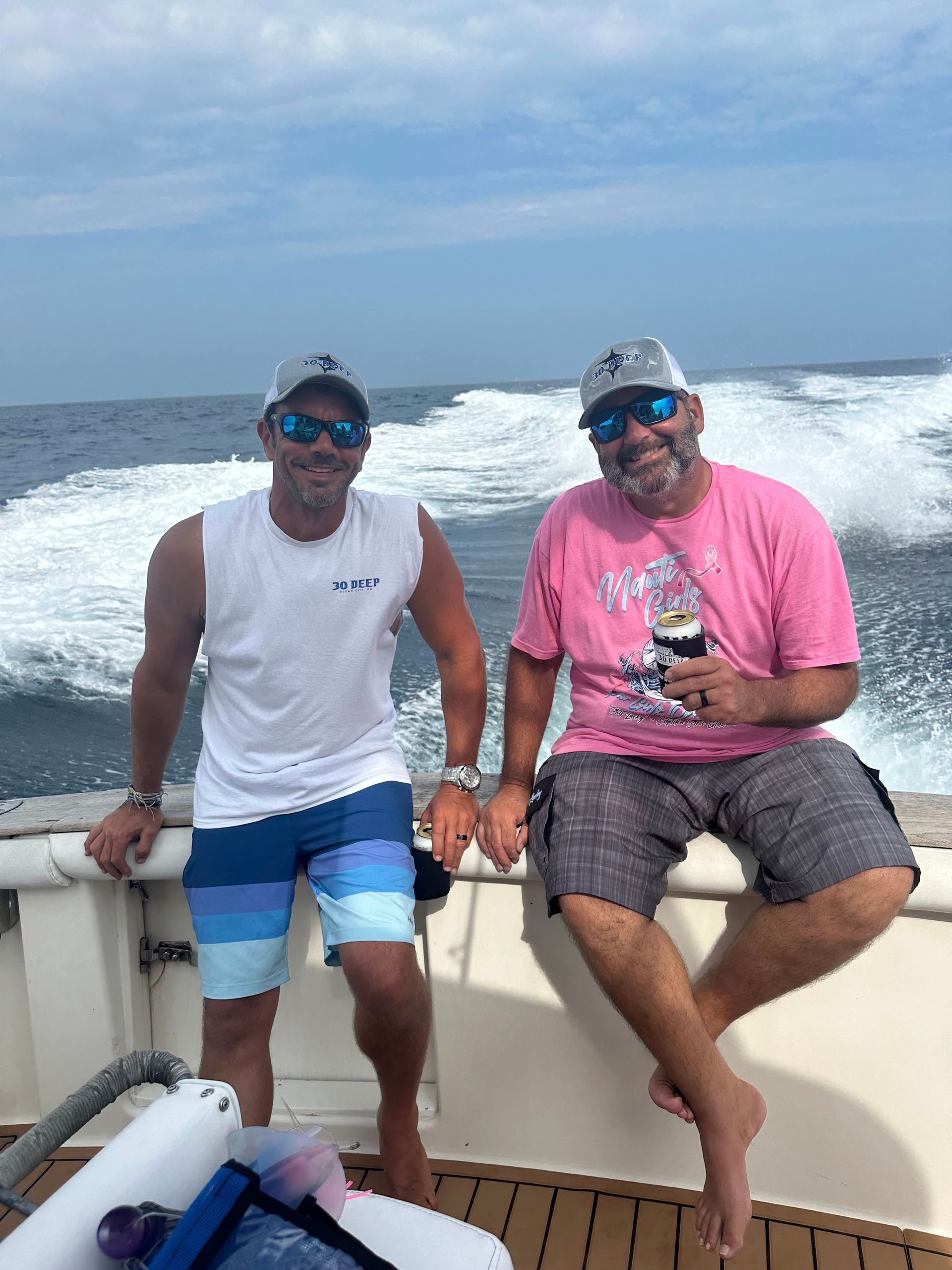 Two men are sitting on the side of a boat in the ocean